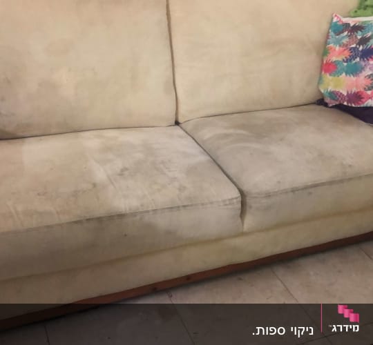 ספה מלוכלכת עם כתמים כהים על הריפוד